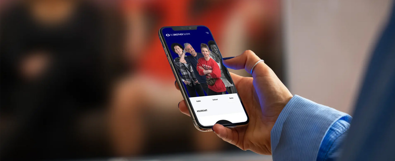 Person holding a mobile device with bigbrother.fi -site visible on the screen.