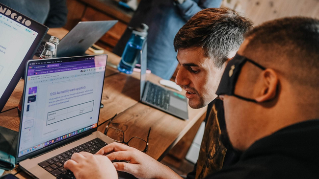 A man is typing blindfolded and another man is giving instructions