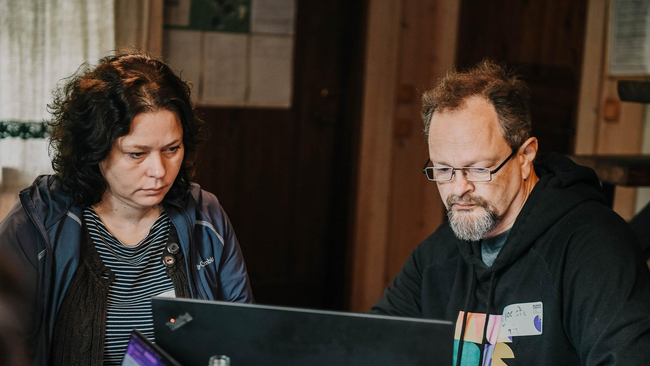 Two persons looking at one PC screen