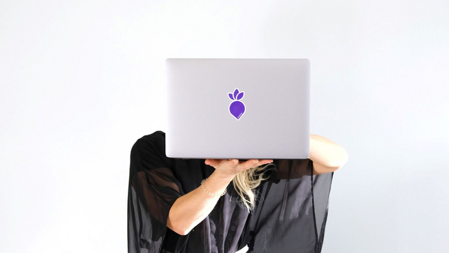A woman with a laptop in her hand helding it in front of her face