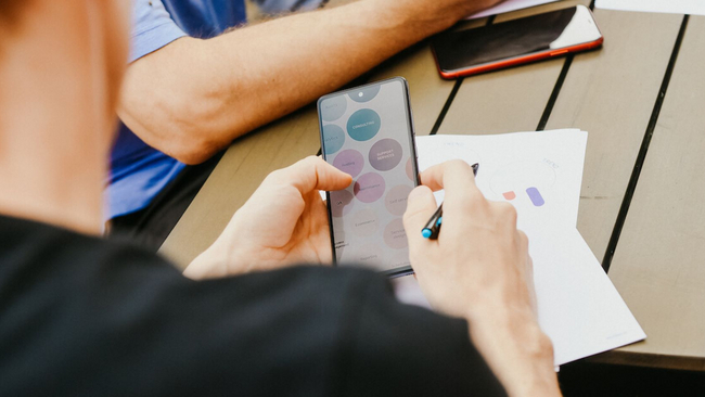 Close up of a person from the back holding a mobile phone.