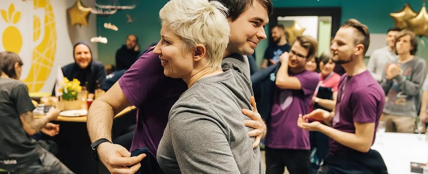 Two smiling people hugging each other