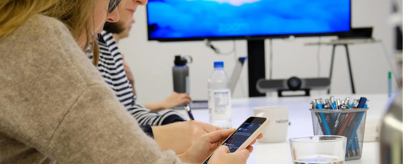 Two people working together, another one is holding a phone