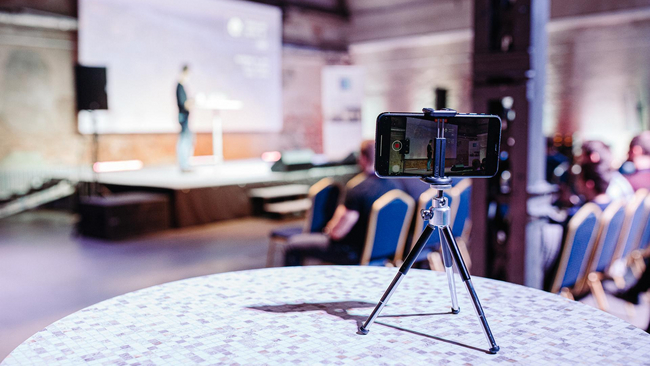 Conference hall with speaker on the stage and phone recordign the speach