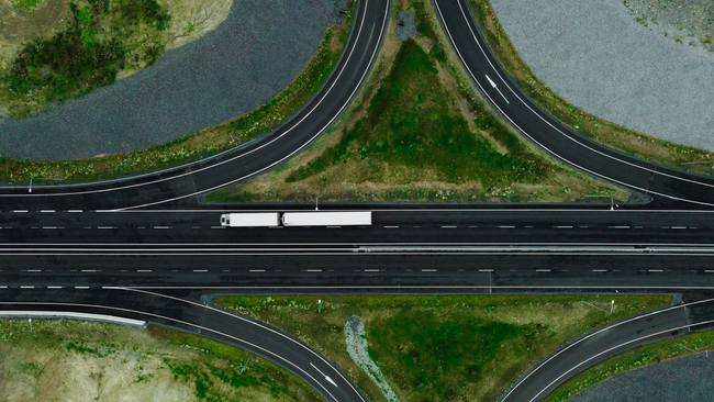 Ilmakuva moottoritiestä, jota ympäröivät vehreät nurmikkoalueet. Kaartuvat erkanevat kaistat muodostavat symmetrisen kuvion.