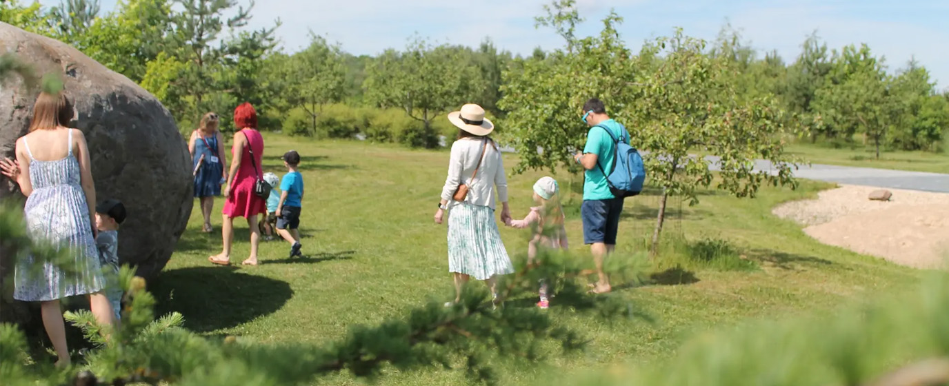 Families walking in the park on a sunny day.