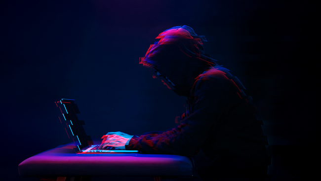 A person in front of a computer in dark lighting